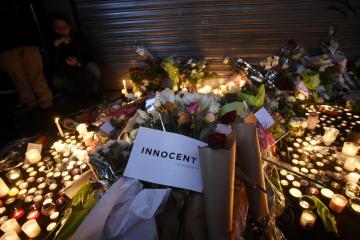 fleurs avec un message disant Innocent au centre de l'image et bougies autour des bouqets de fleur